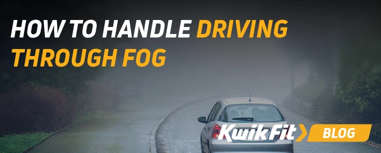 A car drives through heavy fog on a country lane.